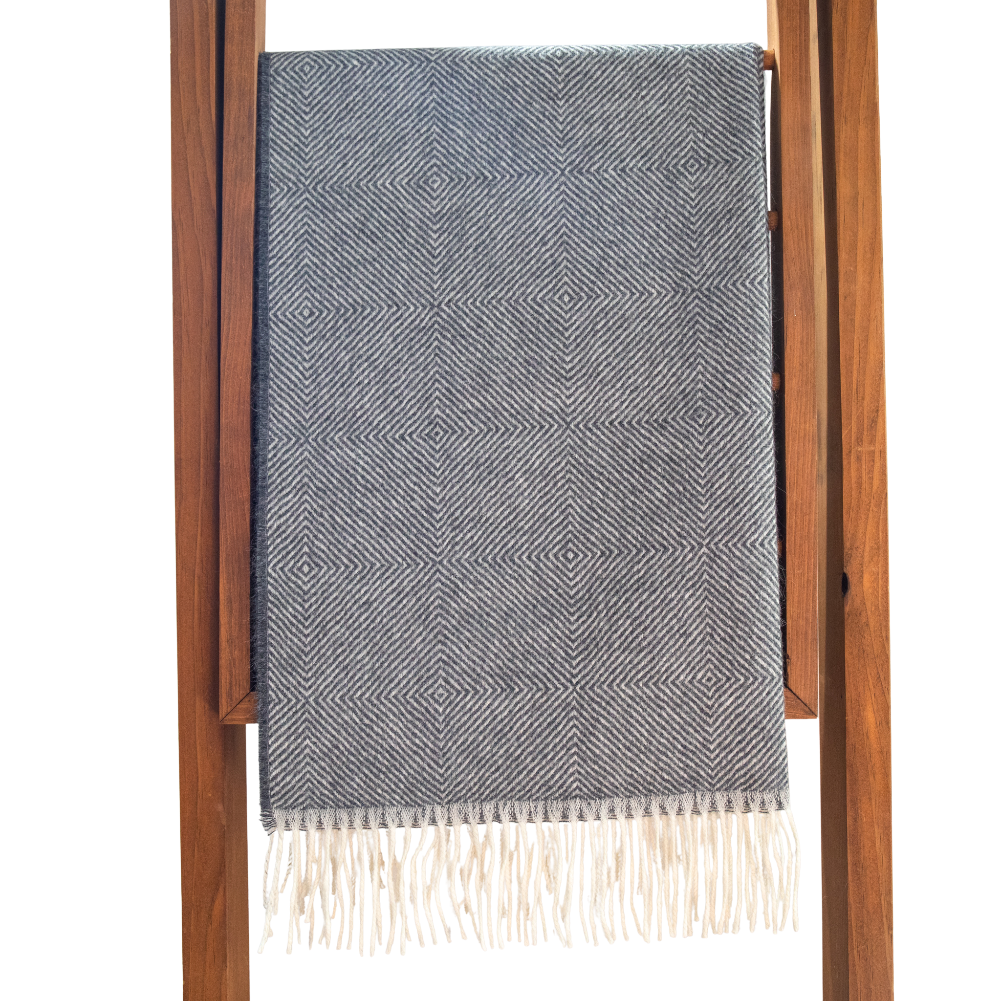 Charcoal patterned throw blanket with white fringe on a wooden ladder