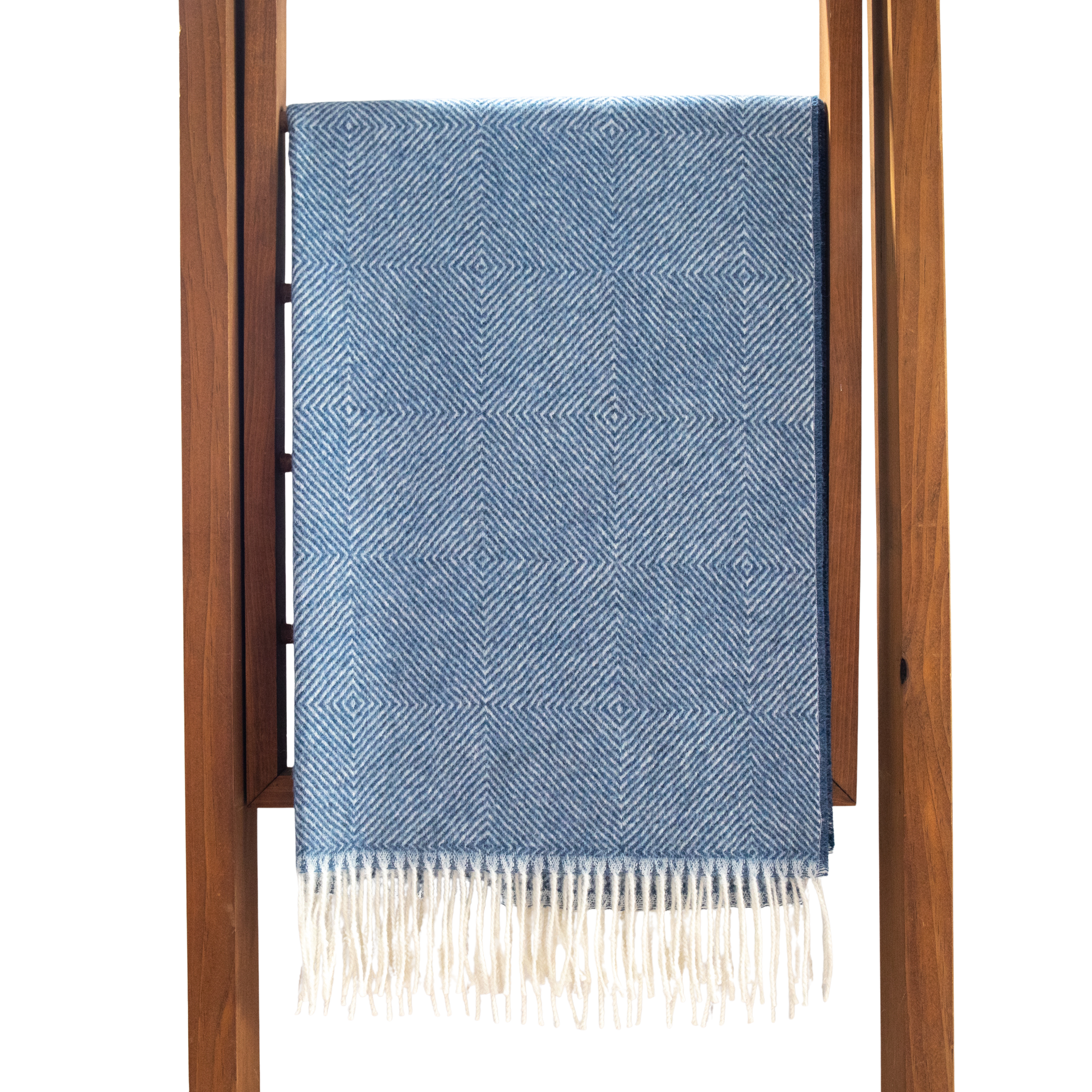 Blue patterned throw blanket with white fringe on a wooden ladder against a white background