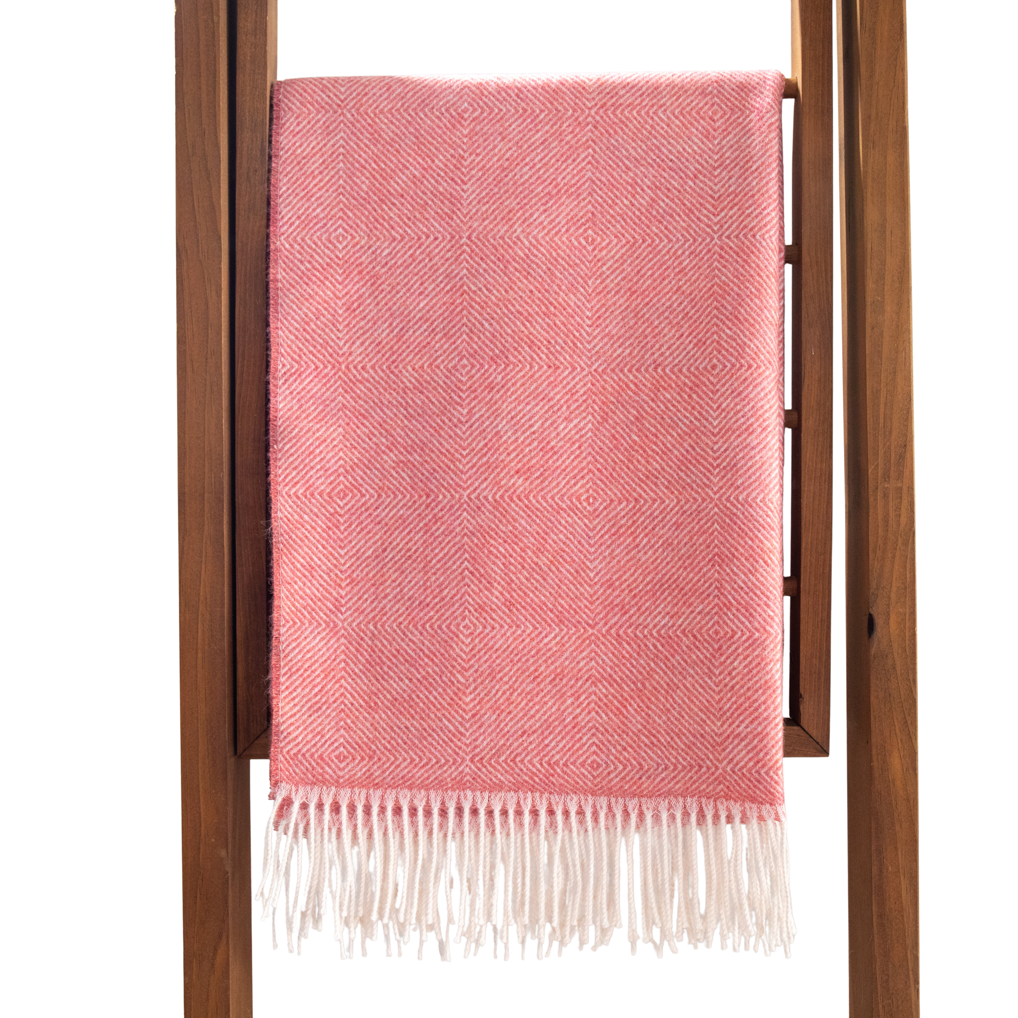 Pink throw blanket with white fringe draped over a wooden ladder on a white background