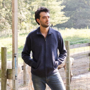 Men's Heavyweight Full-Zip Baby Alpaca Wool Jacket – A man wearing a denim navy knitted baby alpaca wool zip jacket stands in front of an animal enclosure.
