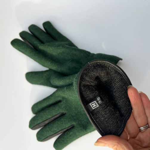 Green gloves with a black interior held by a hand on a white background