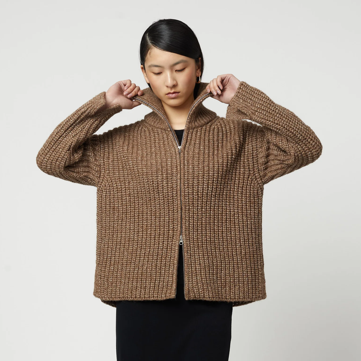 Woman wearing a brown ribbed knit zip-up turtleneck cardigan.