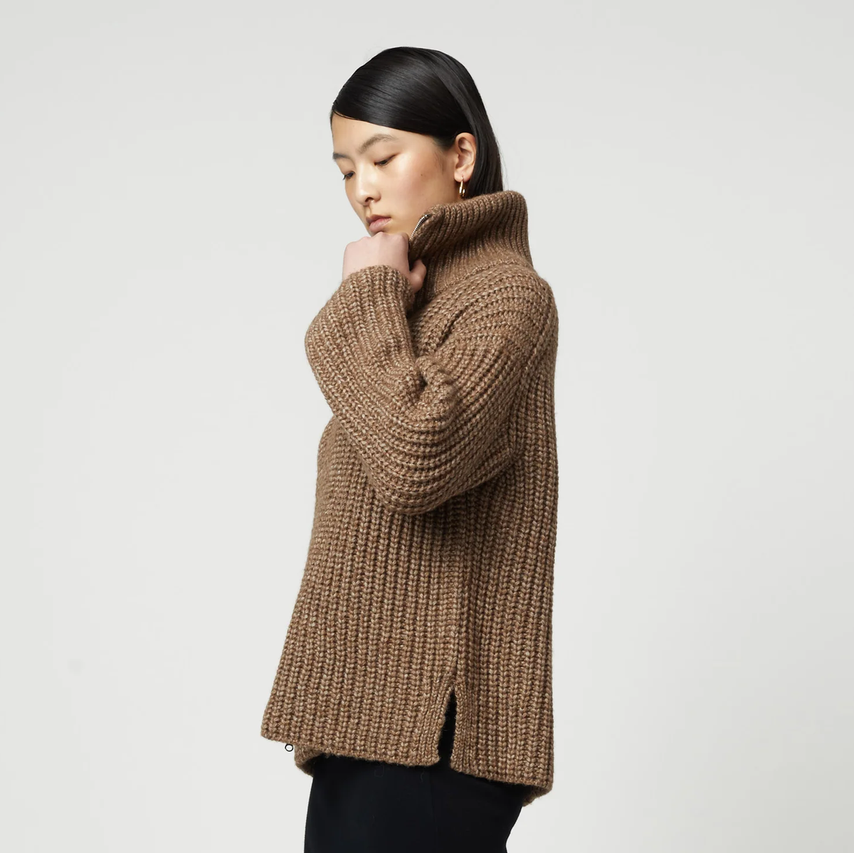Woman wearing a brown ribbed knit zip-up turtleneck cardigan.