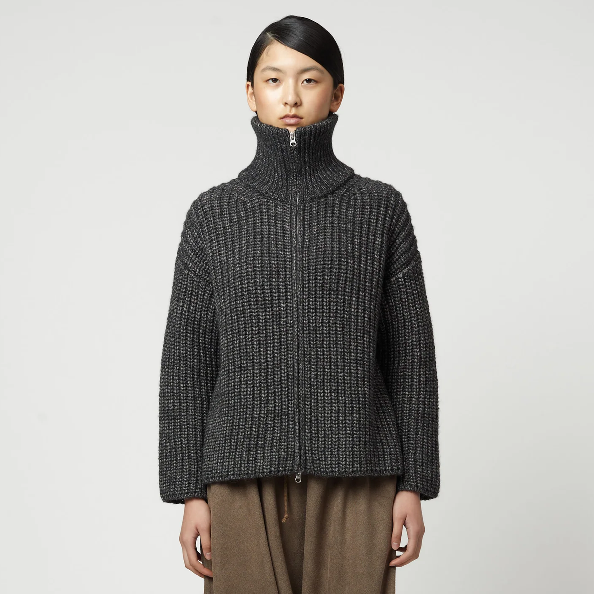 Woman wearing a charcoal grey ribbed knit zip-up turtleneck cardigan.