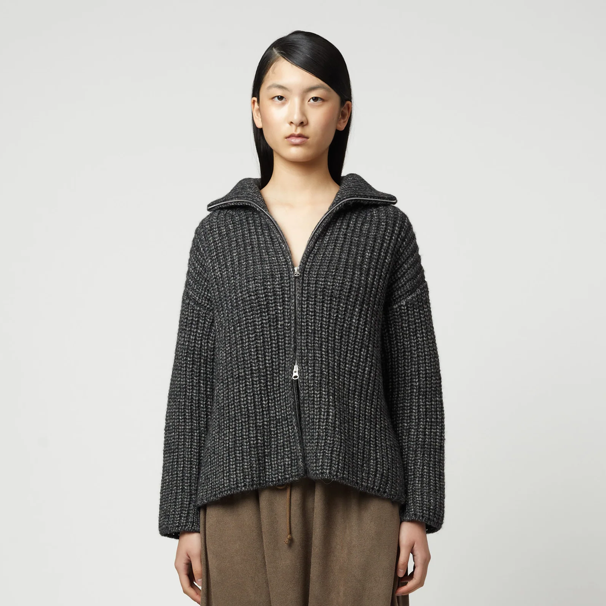 Woman wearing a charcoal grey ribbed knit zip-up turtleneck cardigan.