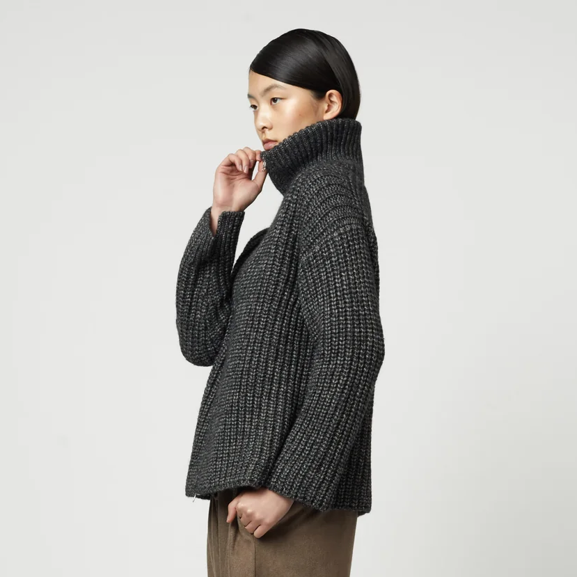 Woman wearing a charcoal grey ribbed knit zip-up turtleneck cardigan.