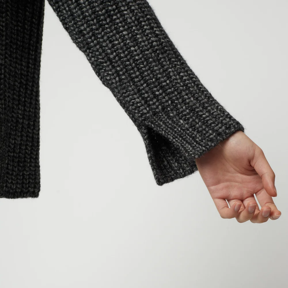 Sleeve detail of a charcoal grey ribbed knit zip-up turtleneck cardigan.