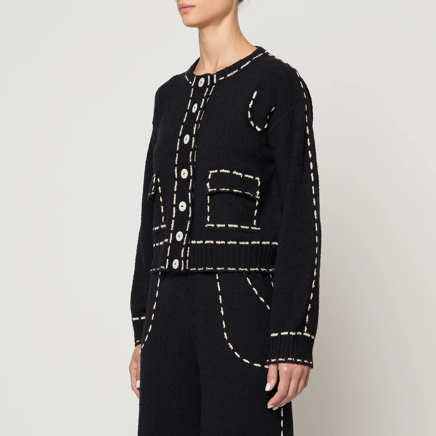Black outfit with tan stitching on a plain background