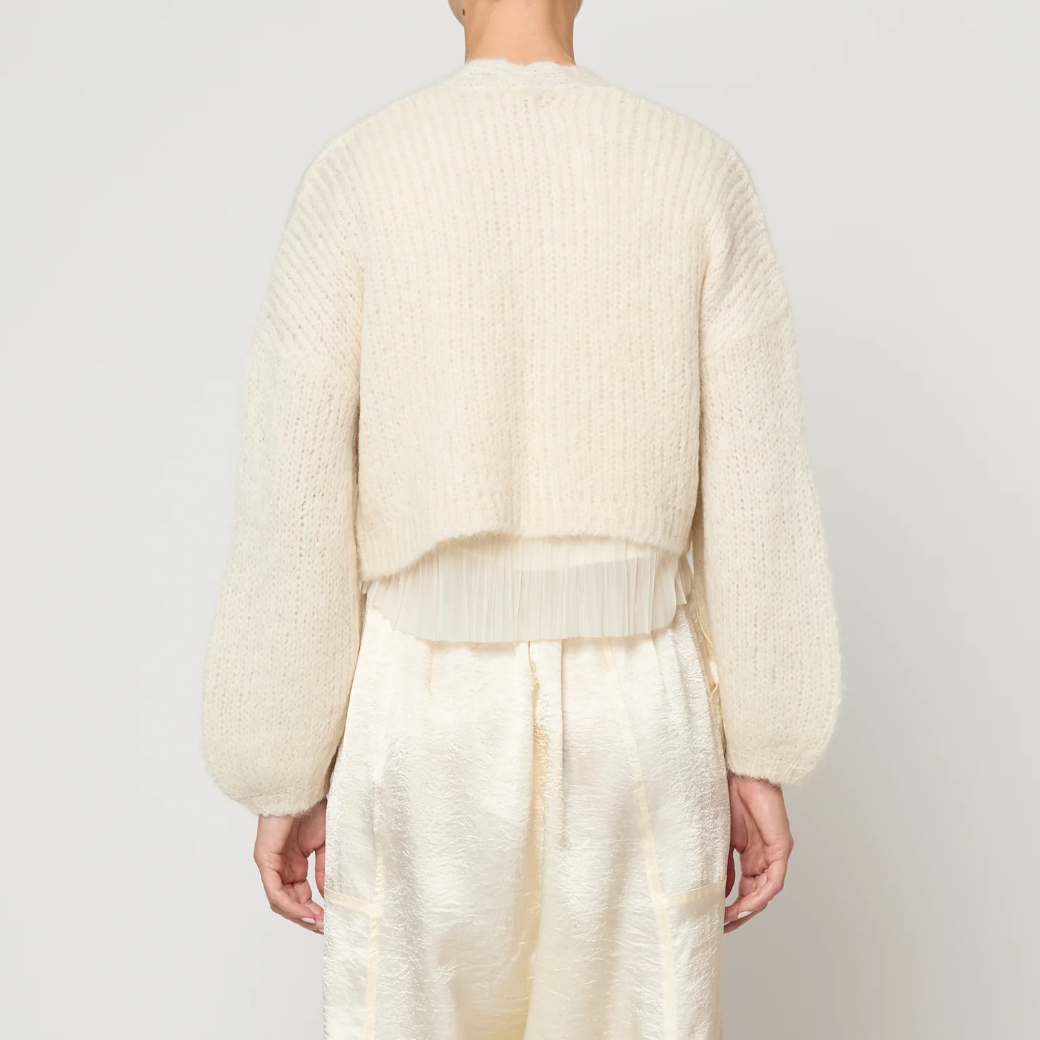 Person wearing a cream-colored outfit against a white background