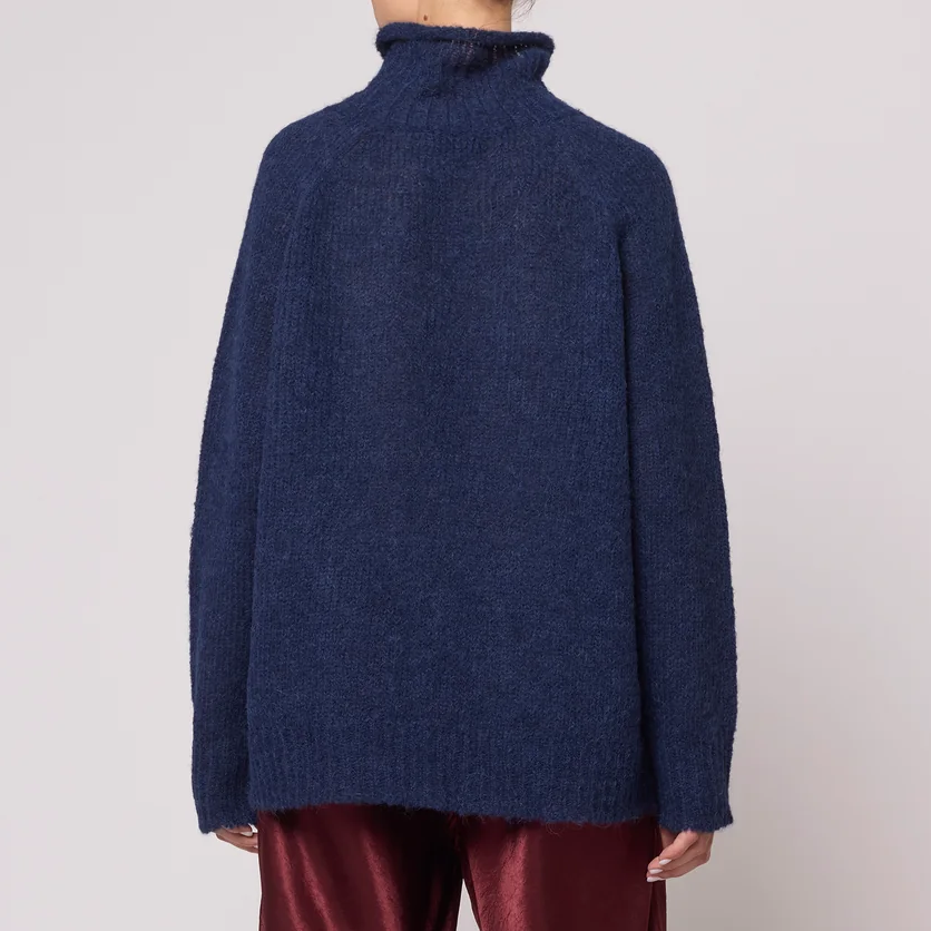 A woman wearing a navy blue knit turtleneck sweater.