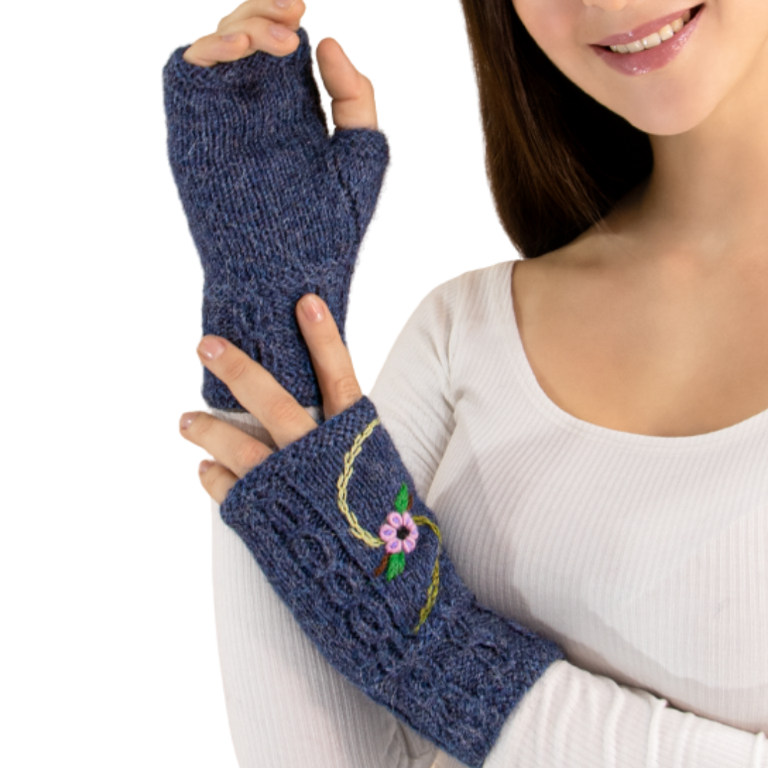Person wearing blue knitted fingerless gloves with floral embroidery on a white background