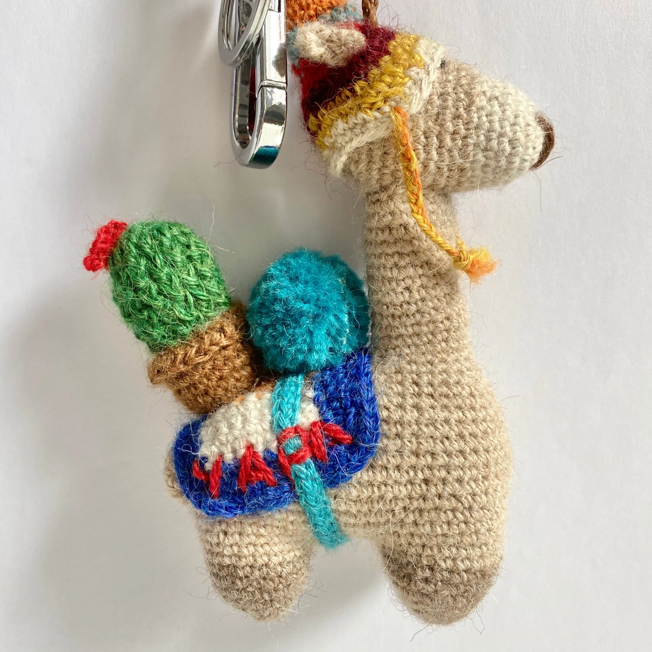Crocheted alpaca keychain with colorful accents on a white background