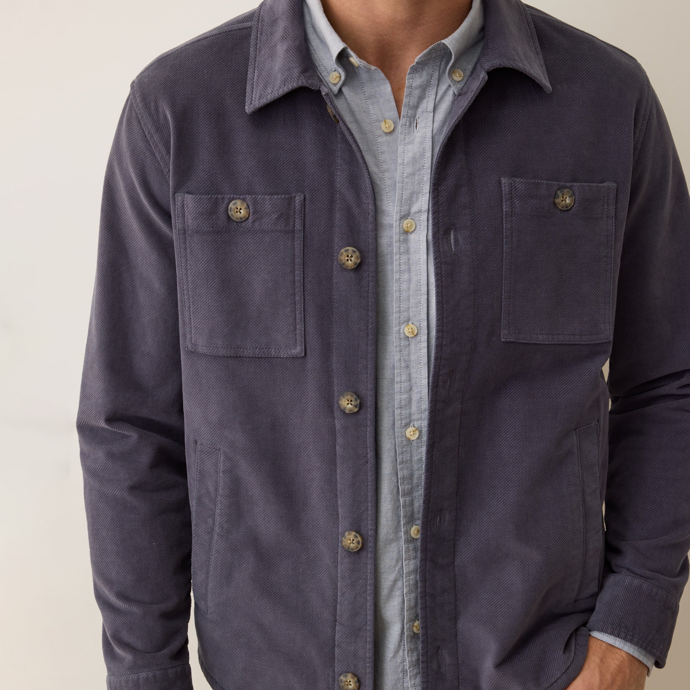 Navy jacket over a light blue shirt on a neutral background