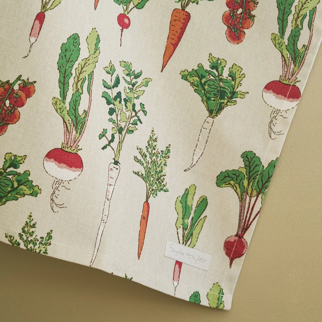 Tea towel with a pattern of illustrated vegetables on a beige background