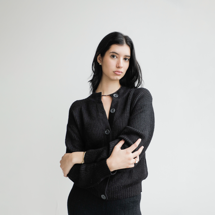 Woman wearing a black cardigan against a plain background