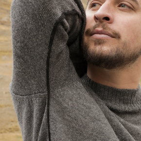 Man wearing a gray sweater with a blurred background