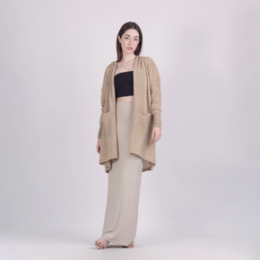 Woman wearing a beige cardigan, black top, and beige pants on a white background