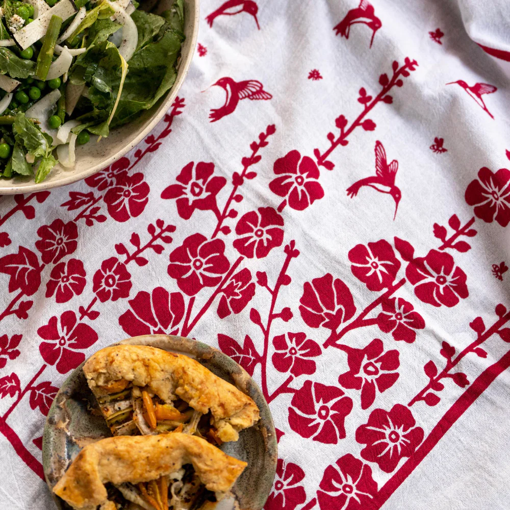 Two bowls of food on a white dish towel with red floral patterns