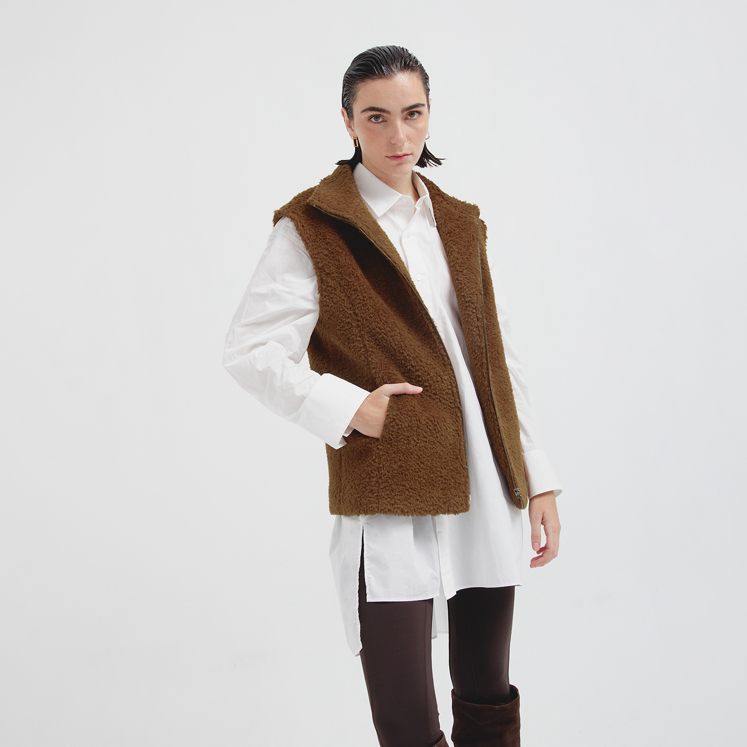 Person wearing a brown vest over a white shirt on a white background