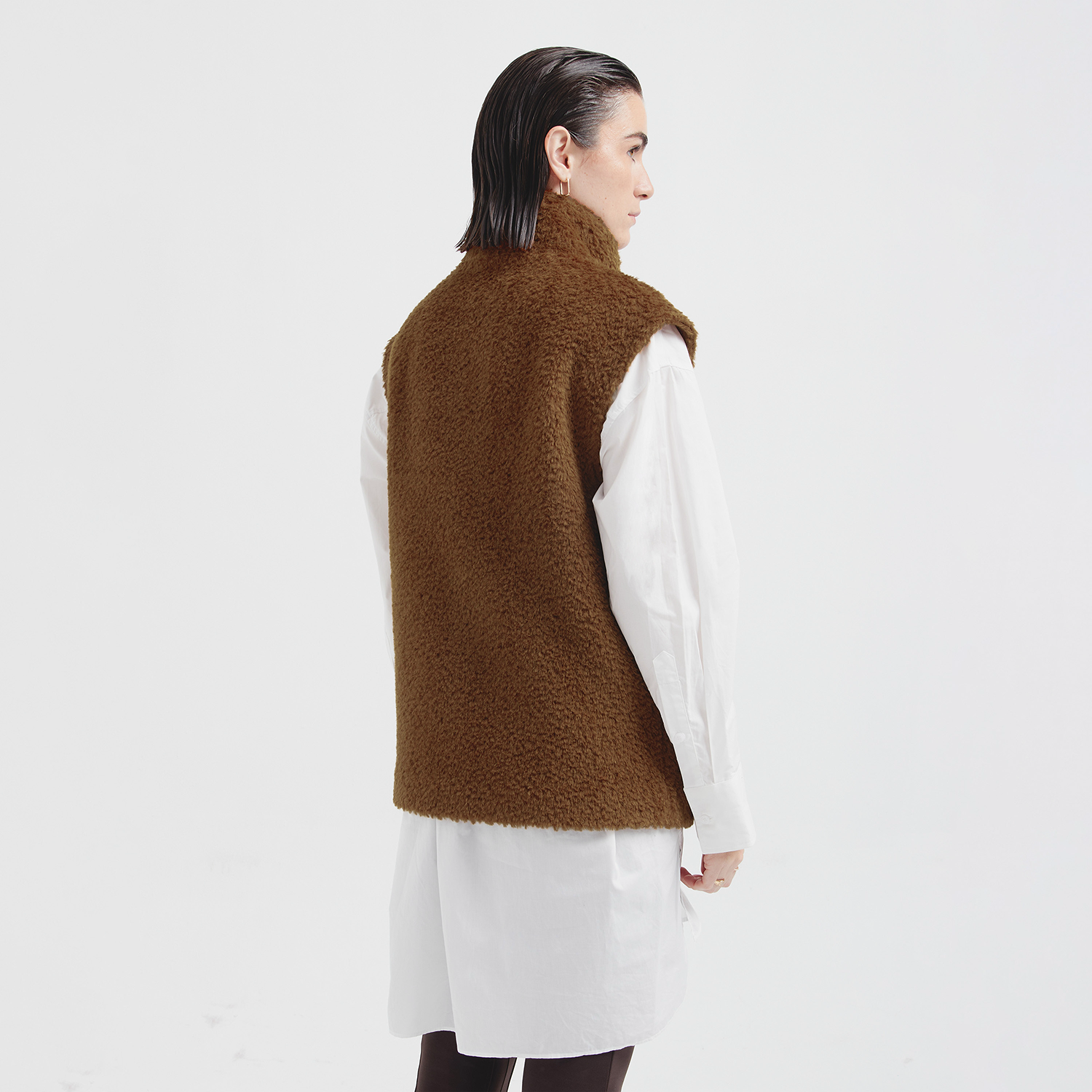 Person wearing a brown fleece vest over a white shirt on a white background