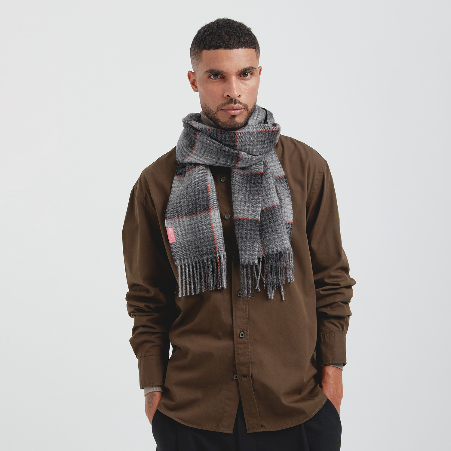 Man wearing a brown shirt and plaid scarf on a white background