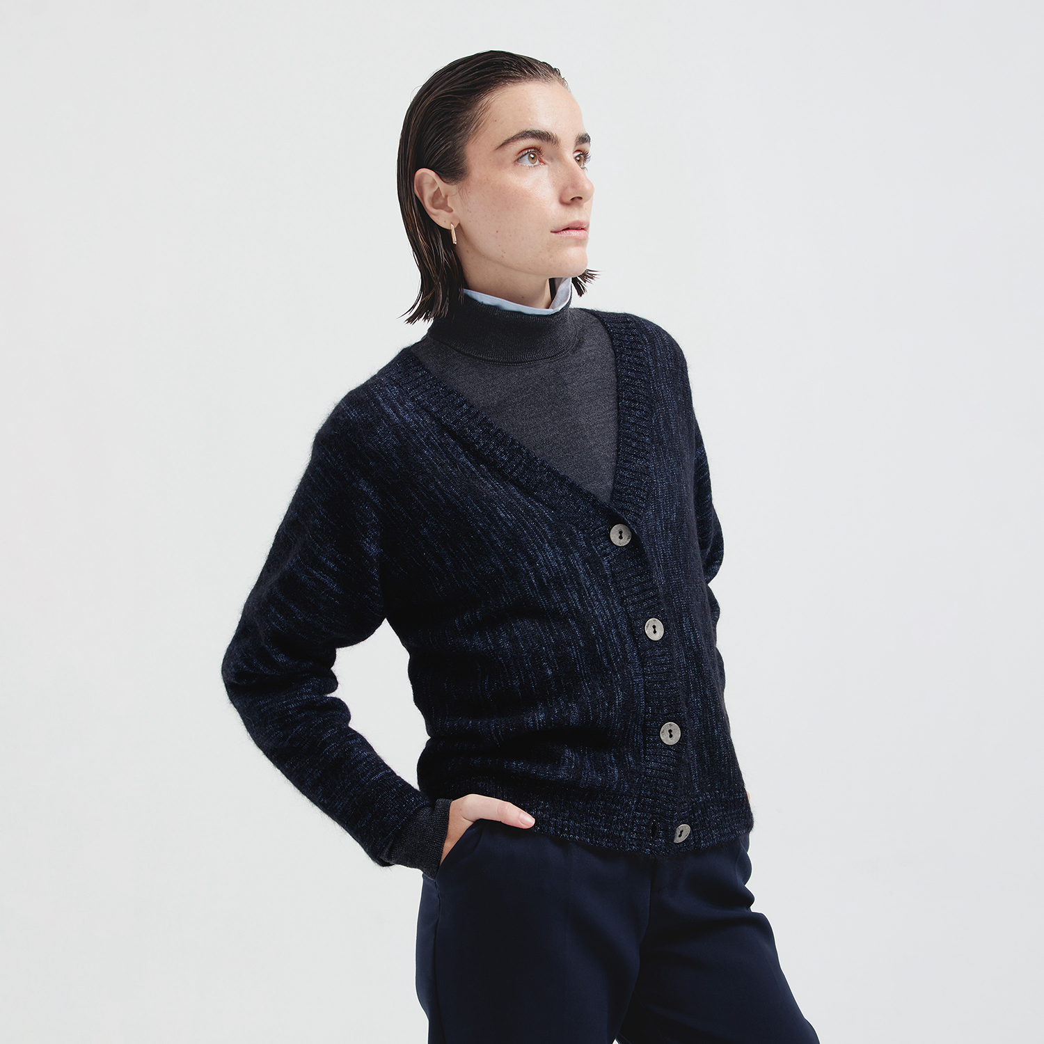 Person wearing a dark blue knitted cardigan on a light gray background
