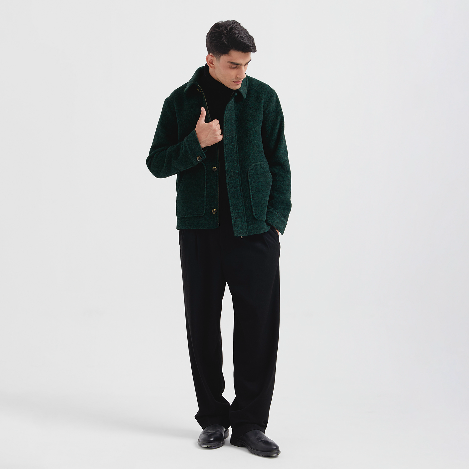Man wearing a green jacket over a black shirt on a white background