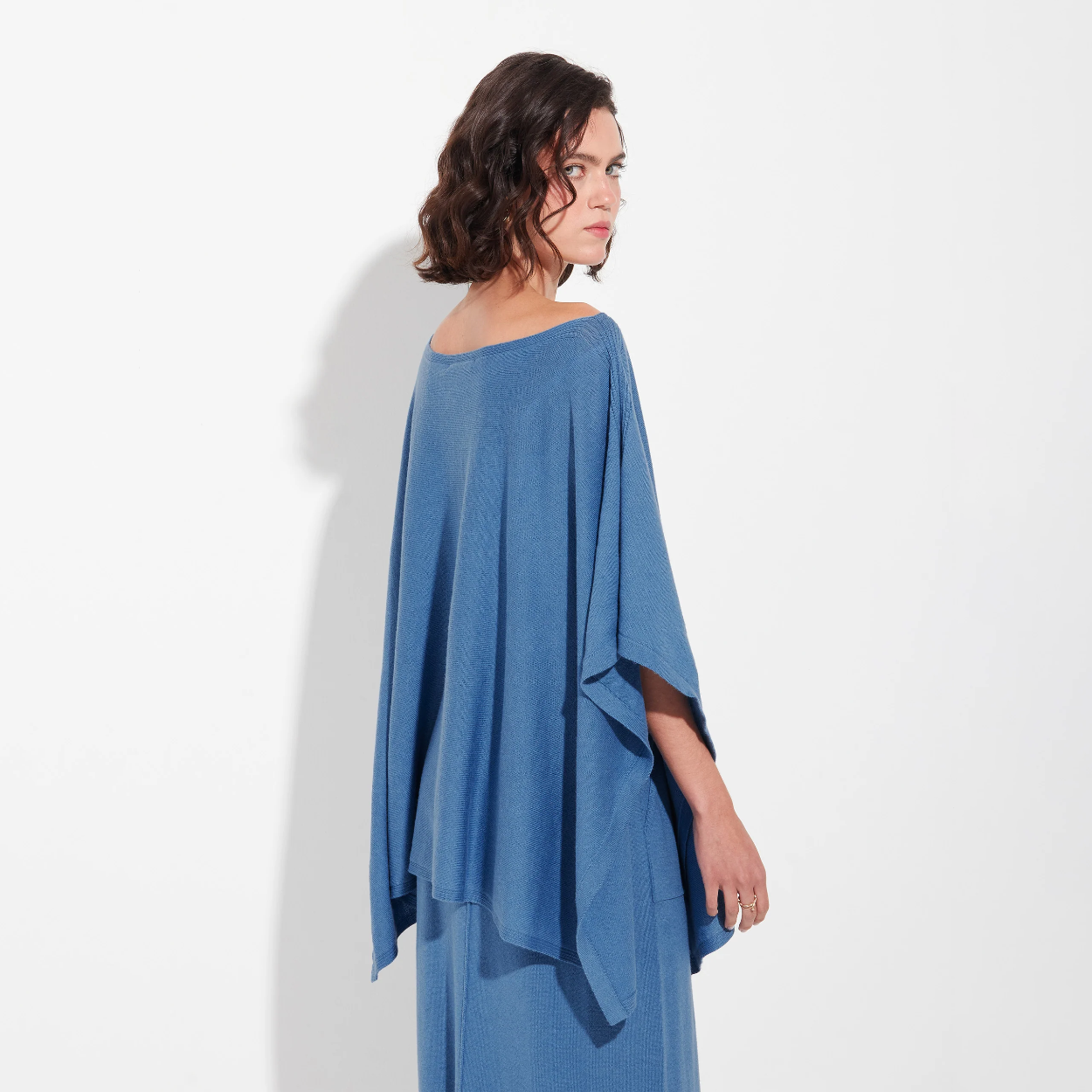 Woman wearing a poncho dress with a plain background