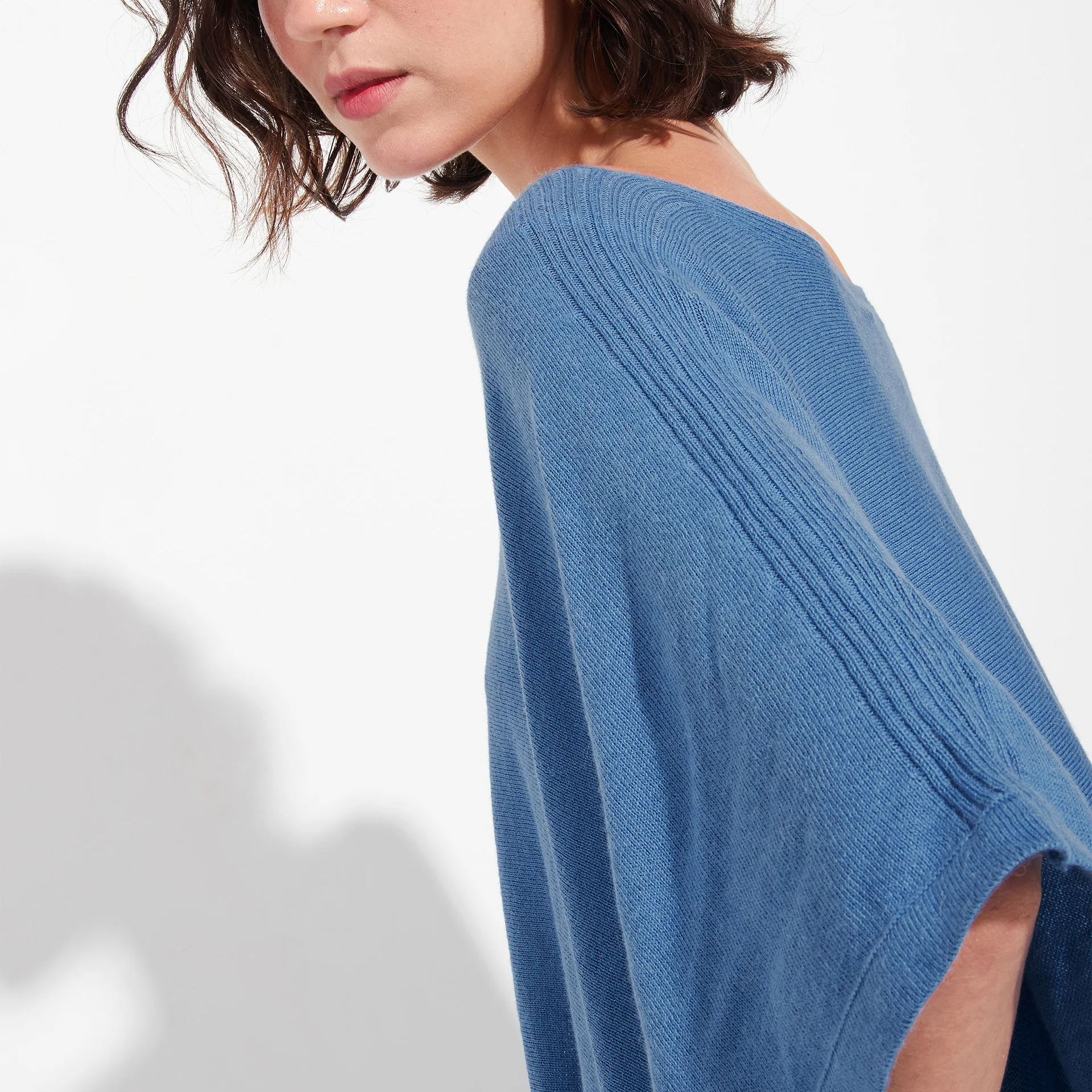 Blue poncho worn by a person on a white background