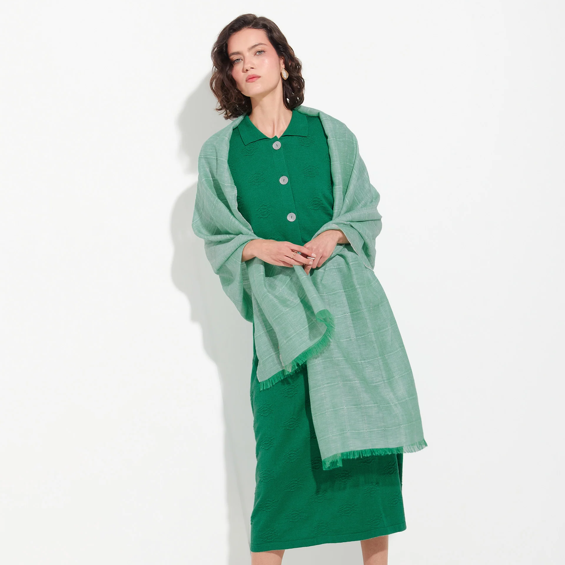 Woman wearing a green outfit with a matching shawl on a white background