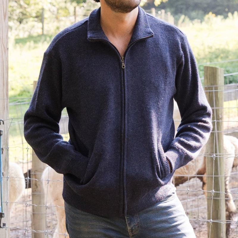 Men's Heavyweight Full-Zip Baby Alpaca Wool Jacket – A man wearing a denim navy knitted baby alpaca wool zip jacket stands in front of an animal enclosure.