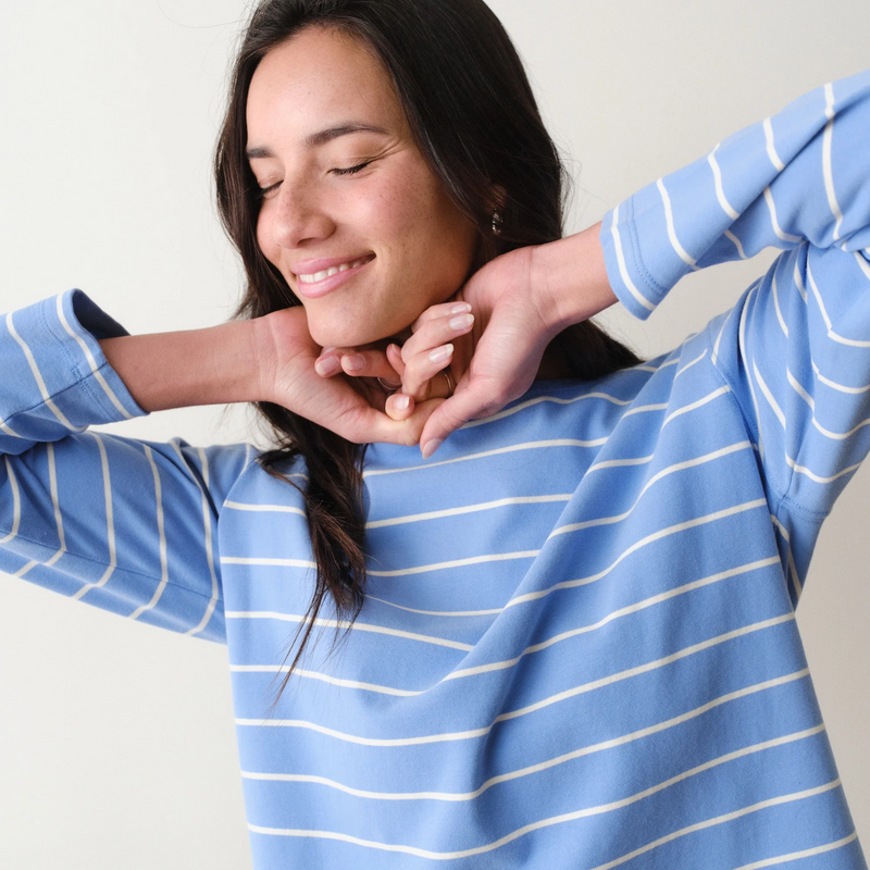 Woman wearing a blue and white striped long sleeved tee with arms outstretched.
