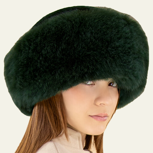 Person wearing a dark green fur hat with a beige background.