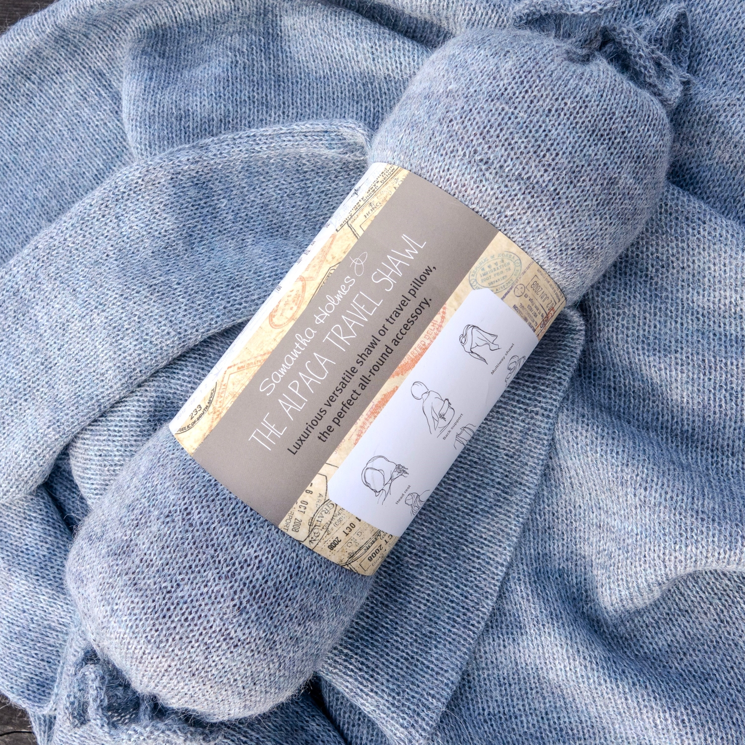 Blue travel shawl with a label on a textured blue background