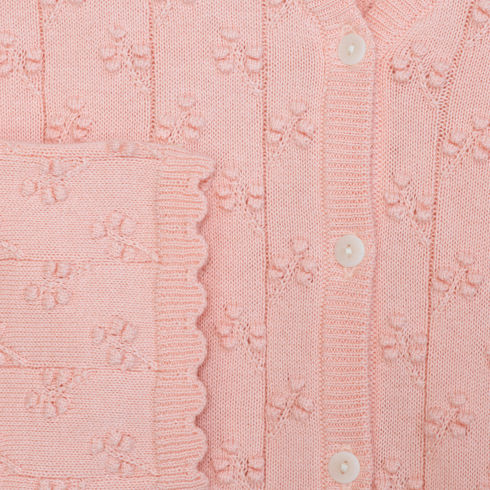 Close-up of a pink textured sweater with button details