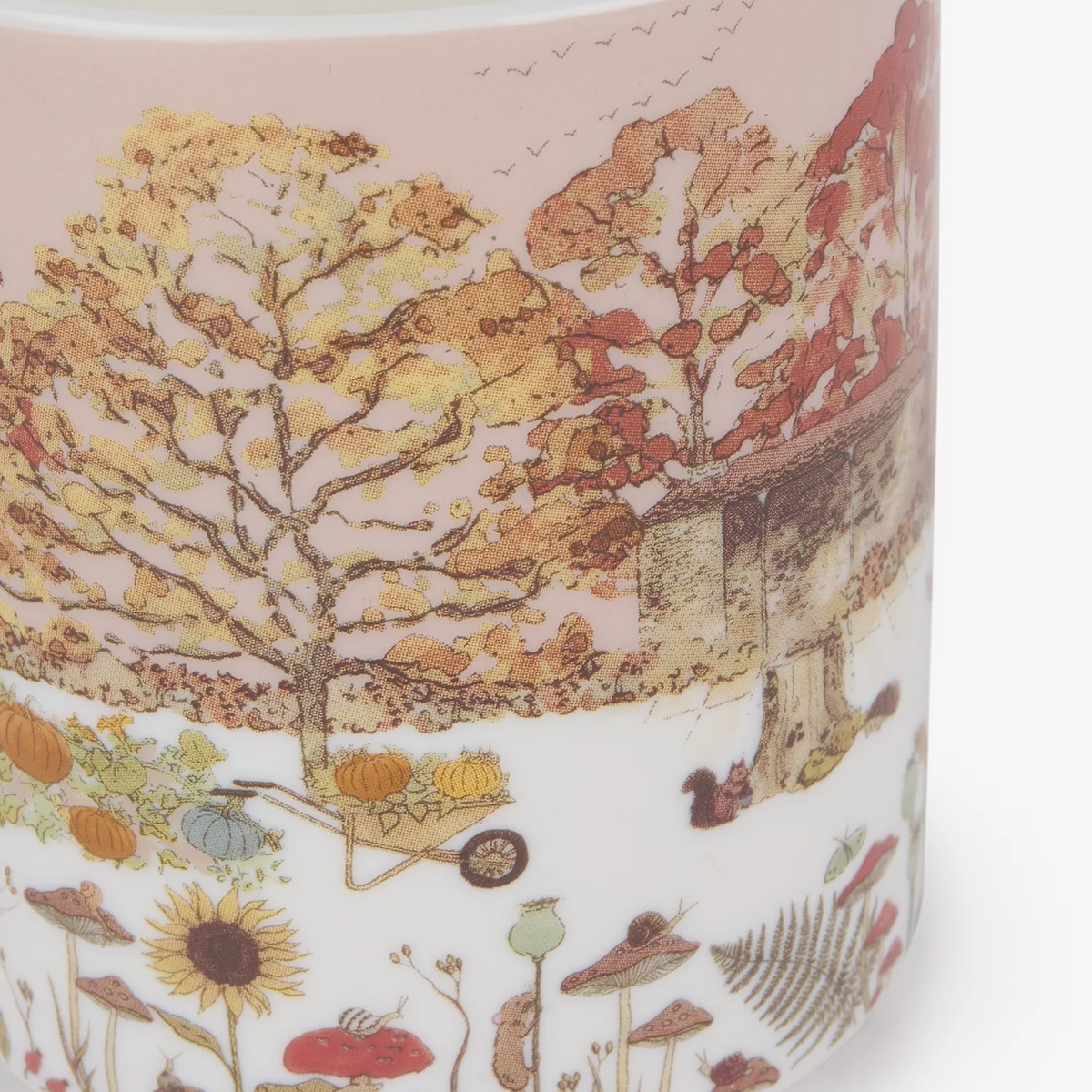 A close-up of a china mug featuring a detailed autumn landscape illustration with trees, pumpkins, flowers, and a rustic cabin on a white background.