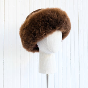 Premium Baby Alpaca Fur Hat. A brown Premium Baby Alpaca Fur Hat on a mannequin head against a white paneled background.