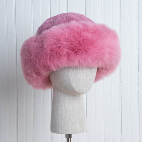 Premium Baby Alpaca Fur Hat. A pink Premium Baby Alpaca Fur Hat on a mannequin head against a white paneled background.
