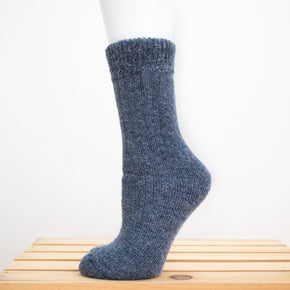 Andinista Alpaca Hiking Socks, a picture of a foot wearing a pair of denim alpaca hiking socks on a wooden crate.