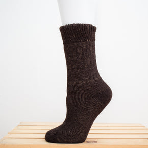 Andinista Alpaca Hiking Socks, a picture of a foot wearing a pair of brown alpaca hiking socks on a wooden crate.