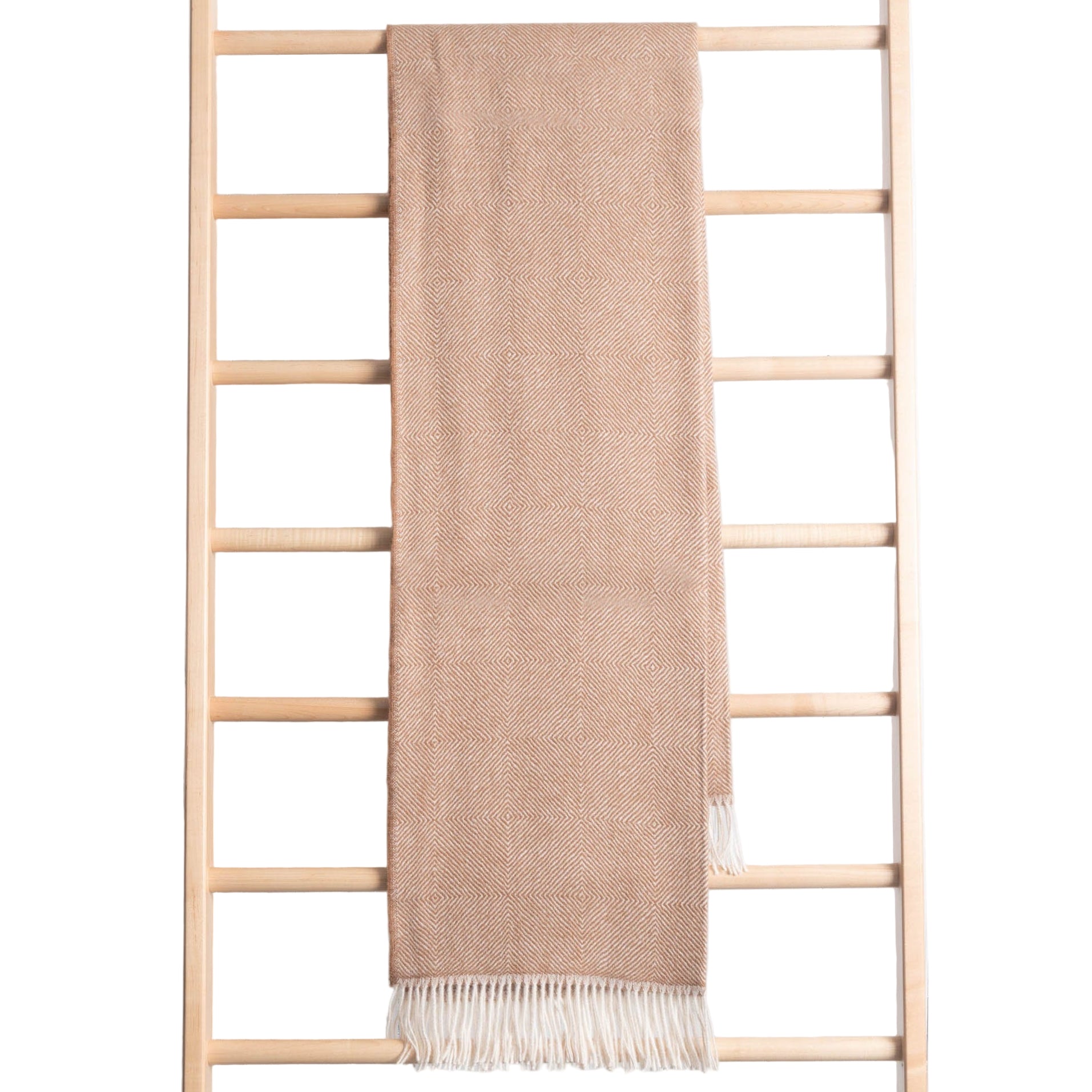 Beige blanket draped over a wooden ladder against a light wooden panel background