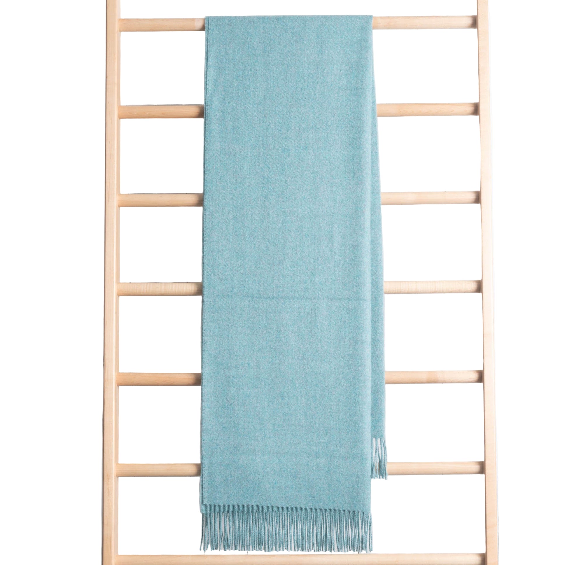 Light blue throw hanging on a wooden ladder against a white wall.