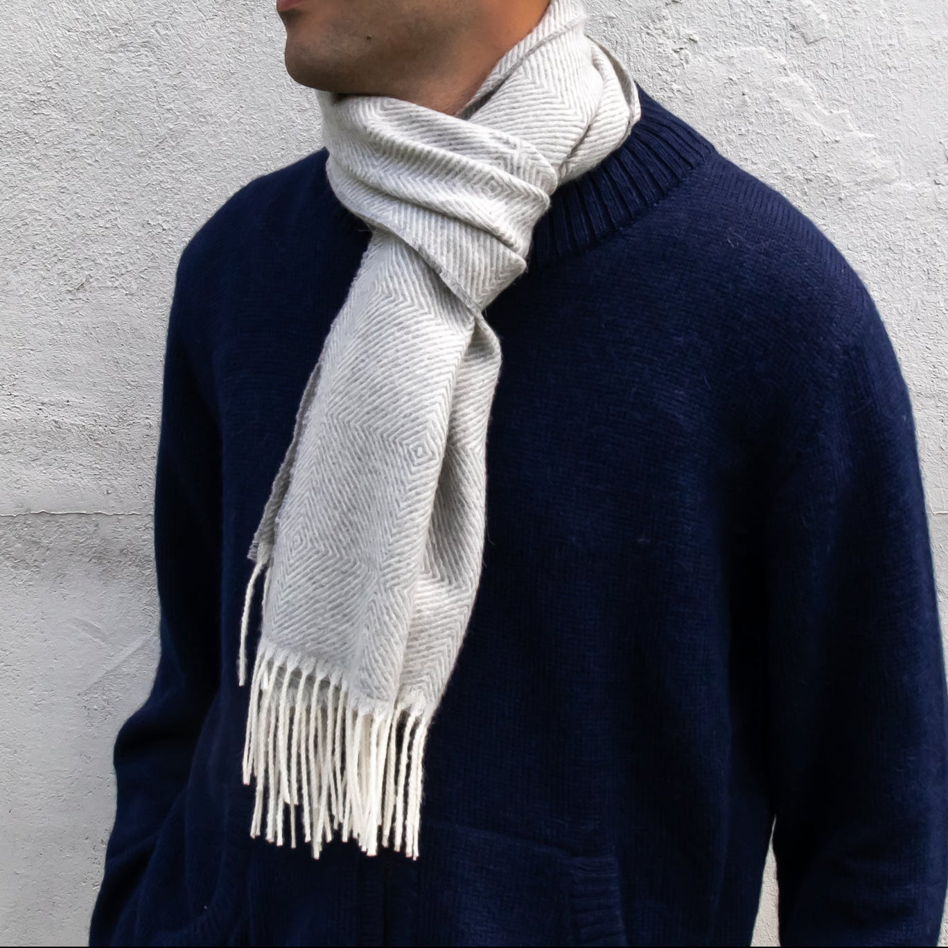 Person wearing a navy sweater and light gray scarf against a light gray background