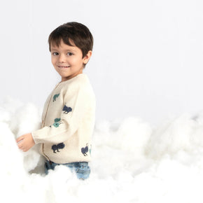 Young boy wearing a white baby alpaca cardigan with blue marching ants in a sea of clouds.
