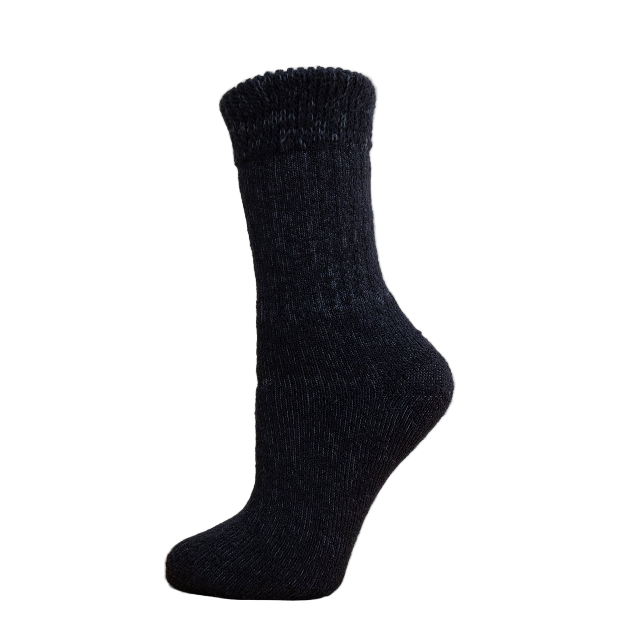 Andinista Alpaca Hiking Socks, a picture of a foot wearing a pair of black alpaca hiking socks on a wooden crate.