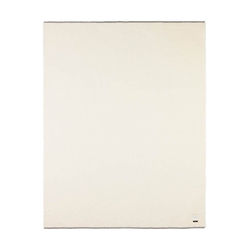 A monochromatic ivory-colored blanket with a rolled hem and blanket stitching.
