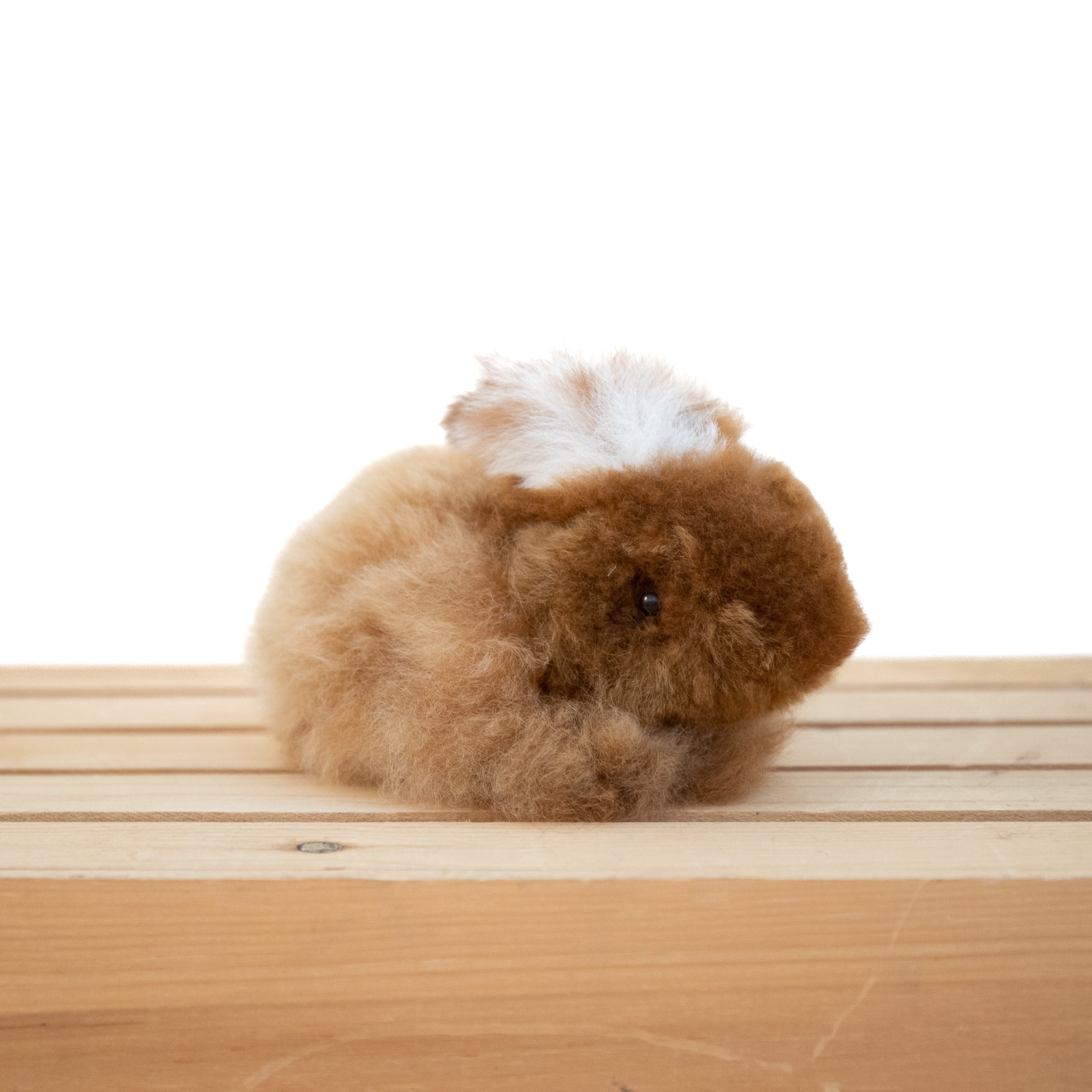 Plush alpaca fur toy bunny on a neutral background