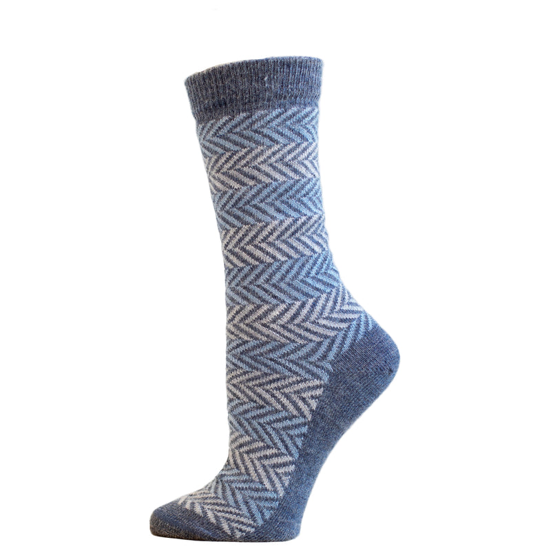 A pair of blue herringbone patterned alpaca socks on a wooden display platform.