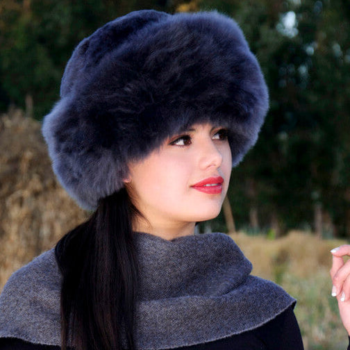 Premium Baby Alpaca Fur Hat. A woman wearing a charcoalPremium Baby Alpaca Fur Hat against a forest background.