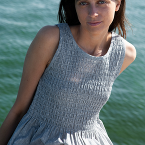 Woman in a light blue dress standing by a body of water